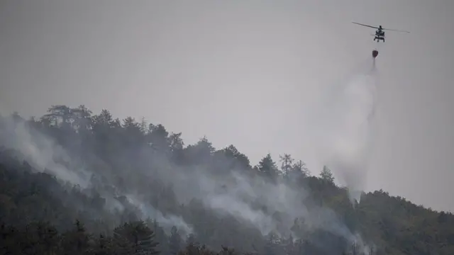 Вертолет сбрасывает воду на горящий лес