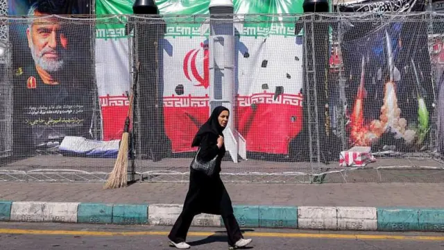 ایران کې یوه ښځه پر دیوال د لګېدلي بنر مخکې تېرېږي