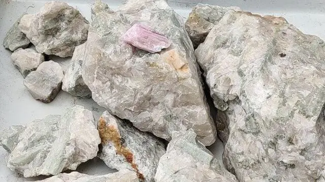 Купа літієвої металевої руди у вигляді каменів світло-сірого, бежевого, рожевого відтінків.