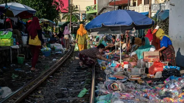 Foto yang diambil pada 8 Juni 2022 ini memperlihatkan pedagang yang berjualan barang di sepanjang rel kereta api Kota Surabaya.