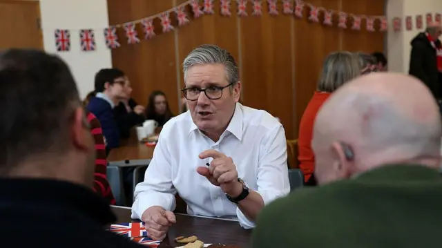 Кир Стармер за столом в белой рубашке