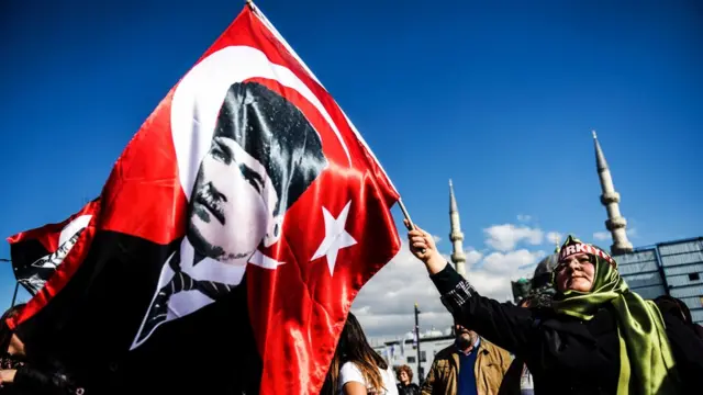 سيدة تحمل علما يحمل صورة أتاتورك مؤسس تركيا الحديثة