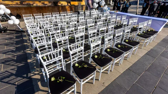 63 bele stolice, na svakoj je bela ruža, a na naslonu ispisana imena žrtava u centru Kočana
