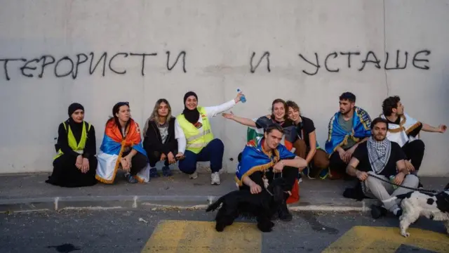 studenti iz novog pazara, studentsko pešačenje iz Novog Pazara, momci i devojke sede ispred zida na kojem su grafiti ustaše i teroristi
