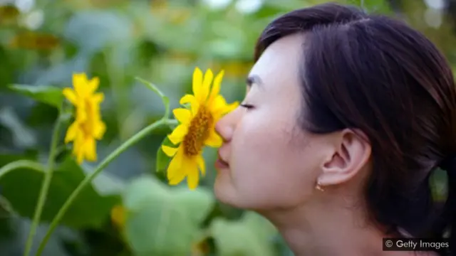 Mulher cheirando flor