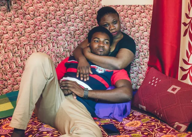 A couple sit on a bed