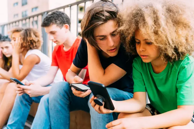 Dečaci gledaju u telefon dok sede napolju