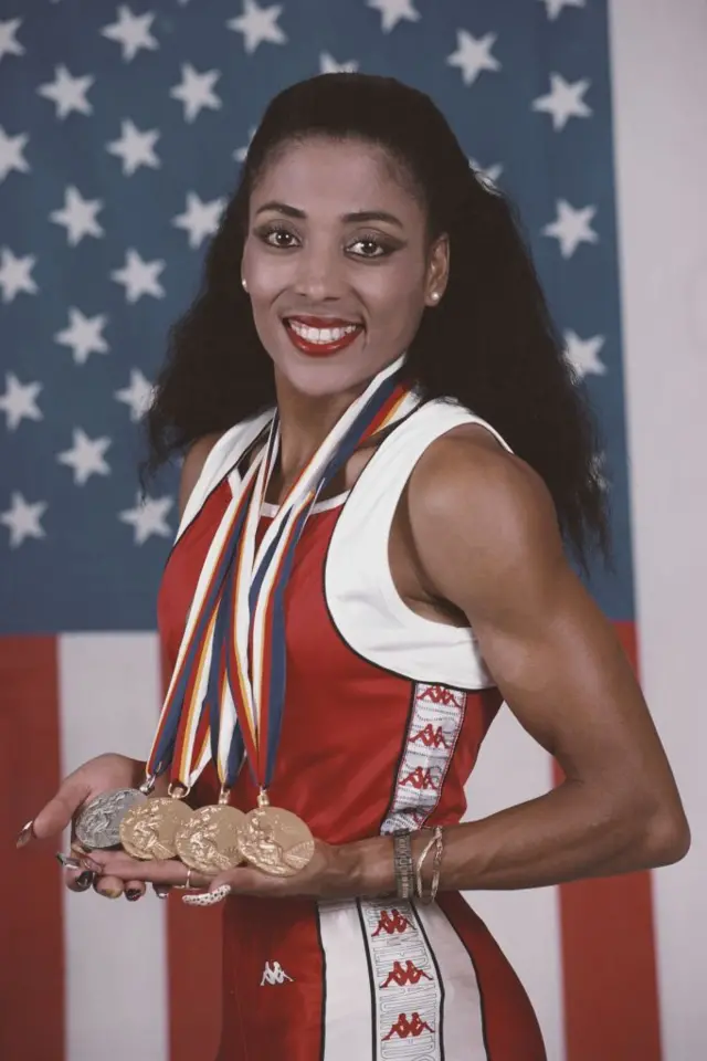Florence Griffith-Joyner pose pour un portrait devant le drapeau américain Stars and Stripes avec ses médailles d'or remportées au relais féminin 100, 200 et 4x100 mètres et l'argent au 200 mètres lors des XXIVe Jeux olympiques d'été le 25 septembre 1988 au stade olympique de Séoul, en Corée du Sud. 