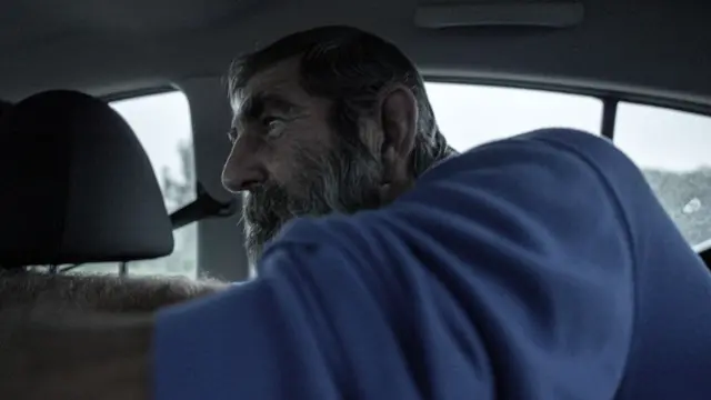 Louis van Schoor à l'arrière d'une voiture, indiquant des emplacements