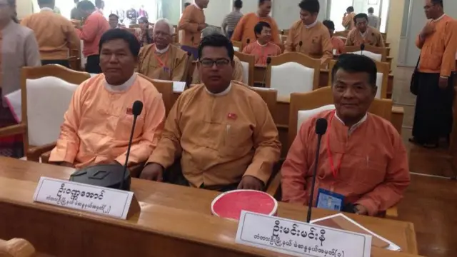 မန္တလေးတိုင်း ပကဖ တာဝန်ခံ ကိုဝဏ္ဏအောင်ဟာ ၂၀၂၀ ရွေးကောက်ပွဲအနိုင်ရ NLD ပါတီရဲ့ လွှတ်တော်ကိုယ်စားလှယ်တစ်ဦးဖြစ်ပါတယ်။ ပင်နီတိုက်ပုံဝတ်အမျိုးသား ၃ ဦးကို ကင်မရာ အရှေ့ဆုံးမှာ တစ်တန်းတည်းထိုင်နေတာတွေ့ရပြီး အလယ်က မျက်မှန်တပ်ထားတဲ့အမျိုးသားရှေ့မှာ ဦးဝဏ္ဏအောင် တံတားဦးမြို့နယ် မဲဆန္ဒယ် အမှတ် ၂ ဆိုပြီး အဖြူအမည်း ဆိုင်းဘုတ်တပ်ထား၊ ဘေးကပ်လျက် ညာဘက်အမျိုးသားရှေ့မှာတော့ ဦးမင်းမင်းနီ တံတားဦးမြို့နယ် မဲဆန္ဒနယ်အမှတ် ၁ လို့ ဆိုင်းဘုတ် အဖြူအမည်း ရေးထား 
