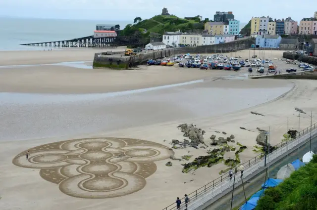 Nghệ sỹ Marc Treanor tạo tác phẩm trên cát ở bờ Bãi Bắc ở Cản Tenby tại Wales.