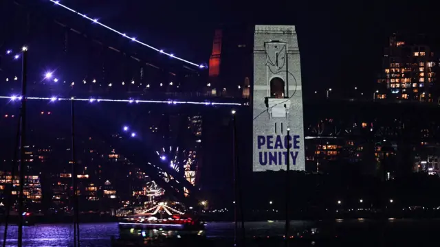A message reading "Peace, Unity" is projected on the pylon of the Sydney Harbour Bridge