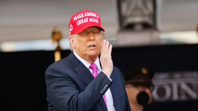 Prezydent USA Donald Trump w czerwonej czapce z napisem Make America Great Again