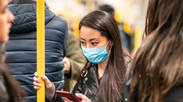 Mulher usando máscara no transporte público