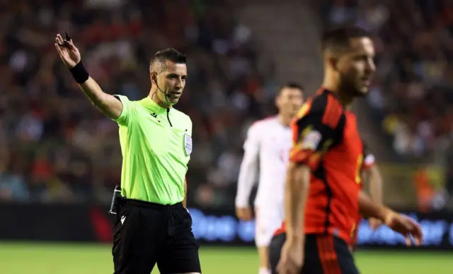 Ali Palabıyık sahada elini kaldırmış, çevresinde futbolcular var