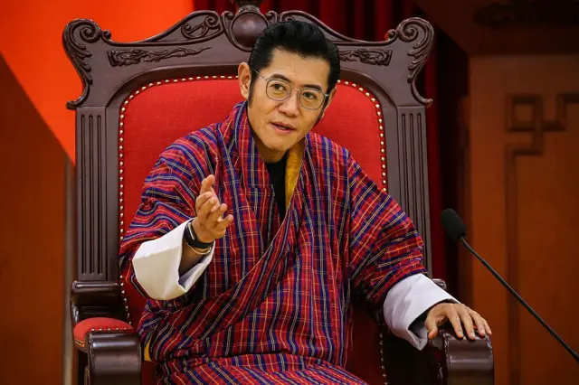 Король Бутана, довольно молодой мужчина в очках, с черными волосами, в национальной одежде.