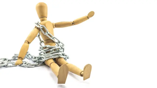 Muñeco de madera encadenado.