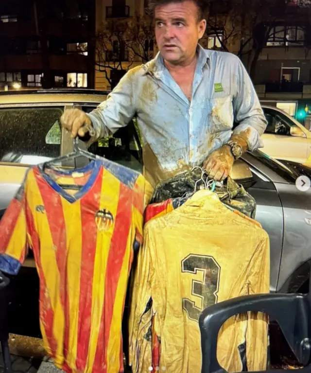 José sujo de barro segurando as camisas enlameadas do seu time de futebol, o Valência
