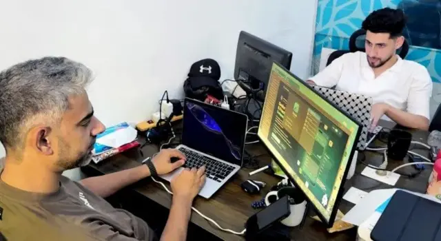 Mahran Bayed wuxuu shaqadiisa ku qabtaa laptop ku xiran shaashad dibadda ah isaga oo jooga Gaza