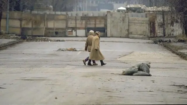 سيدتان تعبران الشارع خلف الجدران الاسمنتية التي تفصل سراييفو عن باقي المناطق في البوسنة خلال الحصار