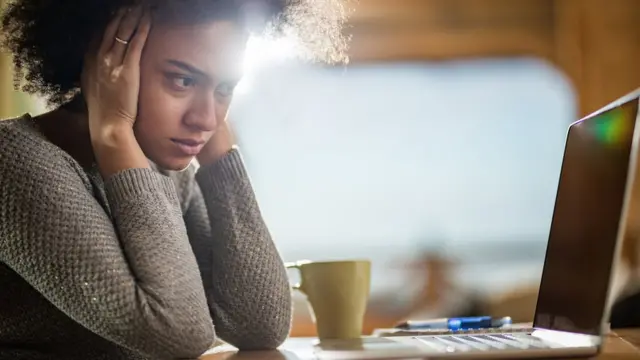 Mulher triste olha para tela do computador