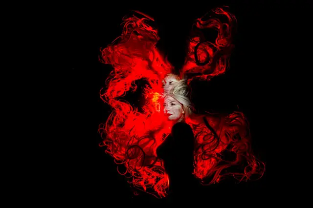 An underwater studio portrait of a woman with hair lit by red light