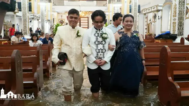 ሙሽራ ከእናት እና አባቱ ጋር በጎርፍ በተጥለቀለቀ ቤተ ክርስቲያን ውስጥ