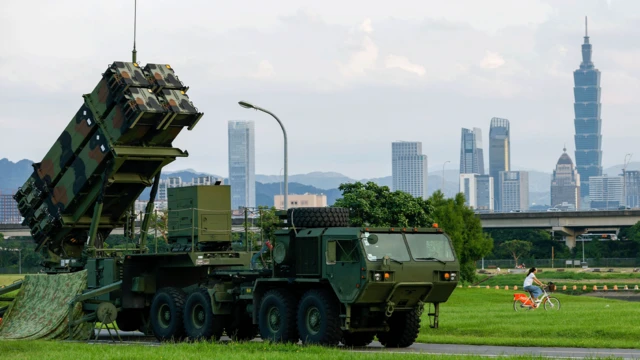 一名騎自行車的人經過台北一座公園,該公園部署了台灣軍方的愛國者防空系統,作為年度漢光軍事演習的一部分