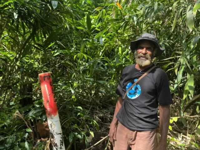 Vincen Kwipalo menunjukkan salah satu patok batas perusahaan yang ia klaim telah memasuki tanah adatnya.