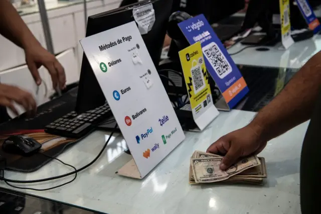 Una persona pagando con dólares en un comercio en Venezuela.
