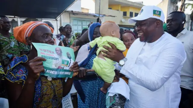 Le candidat à la présidence Paul Hounkpe, du FCBE (Force Cauris pour un Bénin émergent), tient un bébé dans ses bras lors d'un meeting électoral en vue de l'élection présidentielle prévue le 12 avril, à Cotonou, au Bénin, le 1er avril 2026