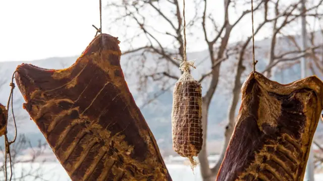 Três grandes pedaços de carne deixados pendurados para secar ao ar livre