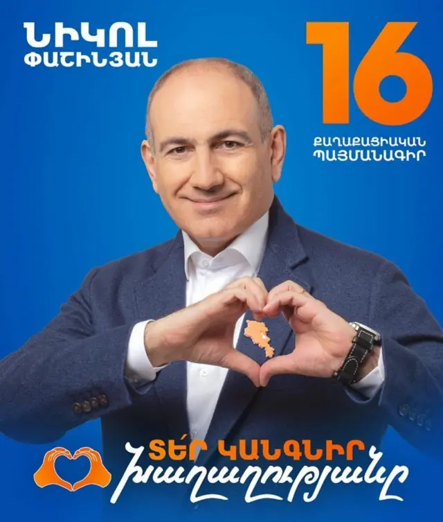 Paşinyan'ın seçim etkinliği için hazırlanmış bir afiş. Siyasetçi, Ermenistan haritasının olduğu turuncu renkli rozeti içine alacak şekilde iki eliyle kalp işareti yapıyor.