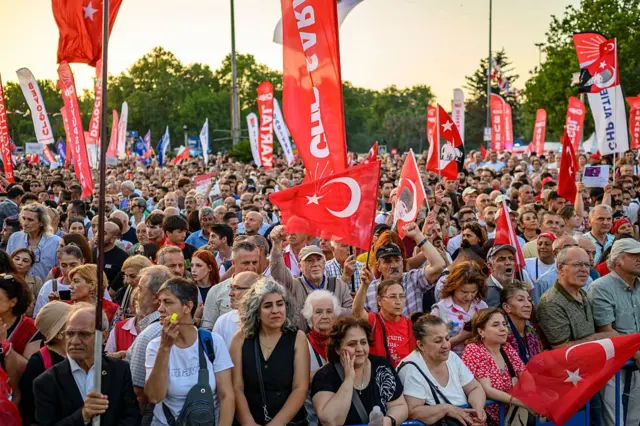 Mitinge katılan orta yaş üstü kadın ve erkekler. Ellerinde Türk bayrakları var.
