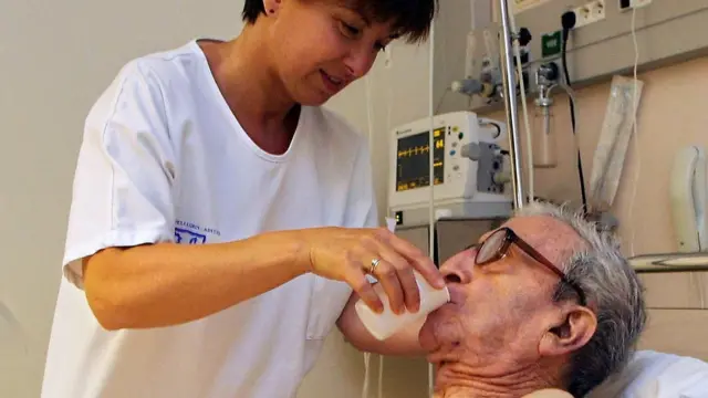 พยาบาลป้อนน้ำให้คนไข้