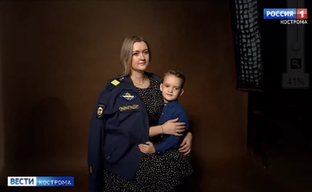 A Russian soldier's wife poses with his uniform