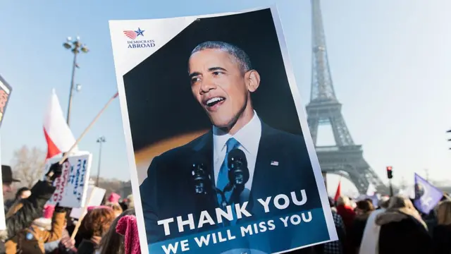 Em Paris, ao pé da Torre Eiffel, manifestante seguran cartaz agradecendo Barack Obama