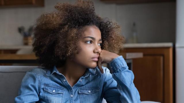 Adolescente negra olha para o lado 