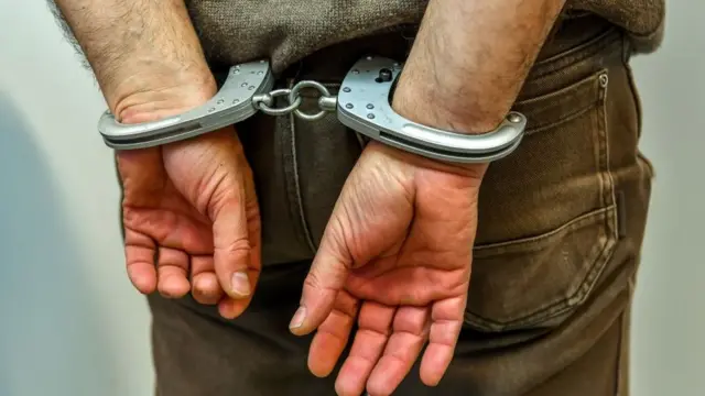 Man wey dem handcuff.
