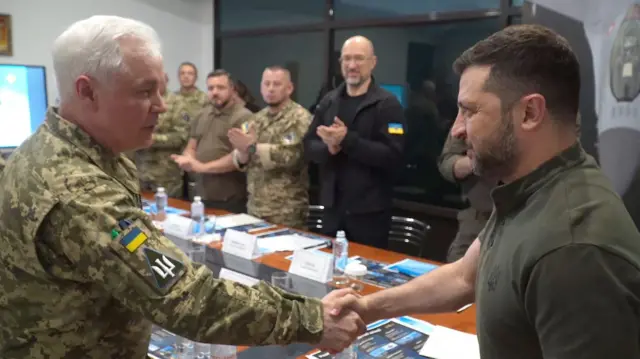 Зеленський і Кривоножко тиснуть одне одному руки на фоні міністра оборони Шмигаля та людей у військовому