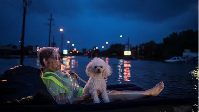 หญิงชรานั่งอยู่บนเบาะนอนเป่าลมกับสุนัขของเธอ ขณะรอรับความช่วยเหลือจากเจ้าหน้าที่ในเมืองฮิวสตัน