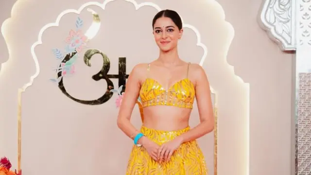 Bollywood star and bridesmaid Ananya Panday shos for one tiger-print yellow lehenga wey dem embroid wit"Anant's Brigade" for di back