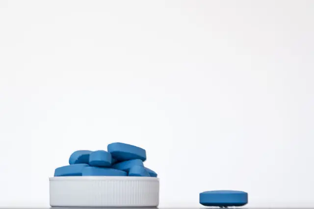 Comprimidos azuis empilhados sobre uma superfície branca. Medicamentos como o Viagra são usados no tratamento da disfunção erétil