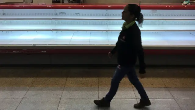 Una mujer pasea frente a una cámara vacía.