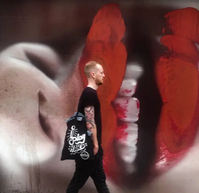 Un hombre pasa frente a un graffiti.