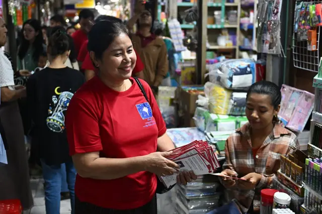 ပန်းဖလက်တွေကိုင်ထားပြီးမဲဆွယ်နေတဲ့ ဒေါ်စန္ဒာမင်းကို စျေးထဲမှာ တွေ့ရစဥ်။
