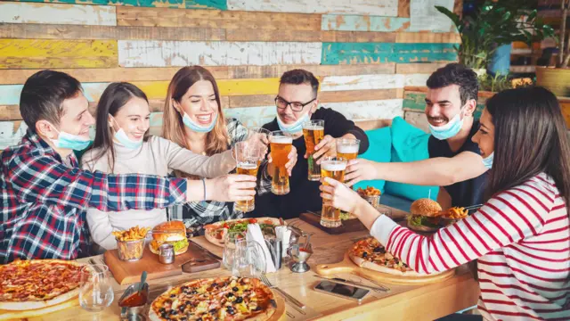 Friends lower their face masks in a restaurant