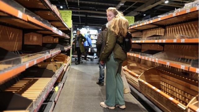 Una mujer mira los estantes de pan vacíos en un supermercado después de que se levantara el toque de queda.