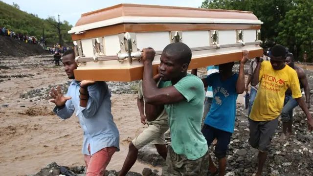 Hombres cargan un féretro mientras atraviesan un río en Haití