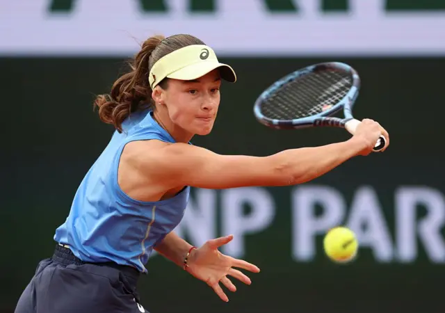Zeynep Sönmez kortta. Kafasında bej rengi bir şapka ve üzerinde mavi tenis üniforması var.
